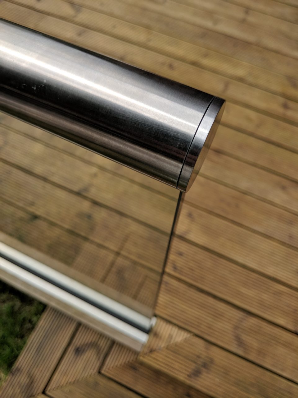 Slotted end cap on slotted handrail installed ontop a glass balustrade on decking